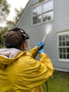Power washing a house with a pressure washer